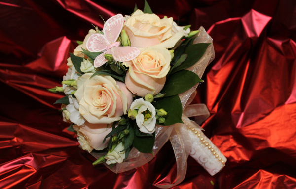 Нежный свадебный букет с цветами розовой розы и эустомы на красном фоне