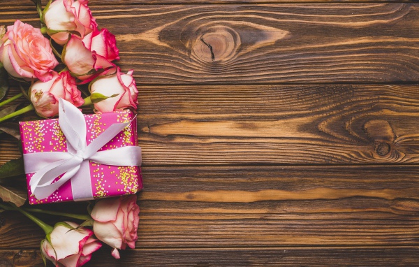 Подарочная коробка с букетом роз на деревянном фоне 