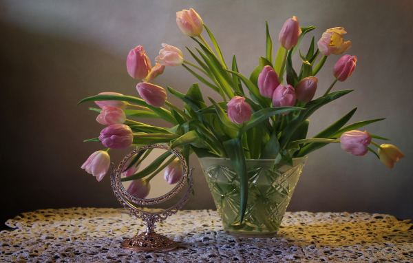 Розовые тюльпаны в стеклянной вазе на столе с зеркалом 