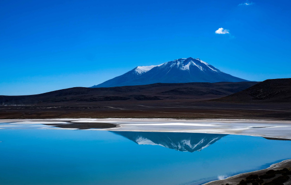 Гора отражается в воде на фоне голубого неба