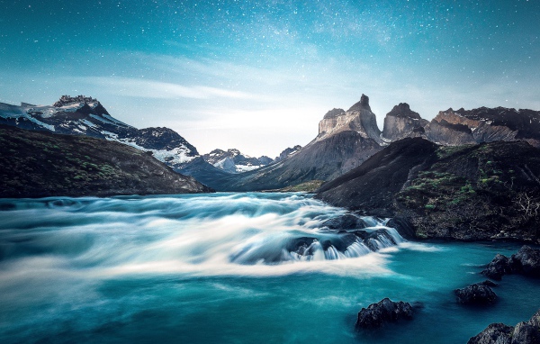 Быстрая вода к реке у гор на фоне голубого неба 