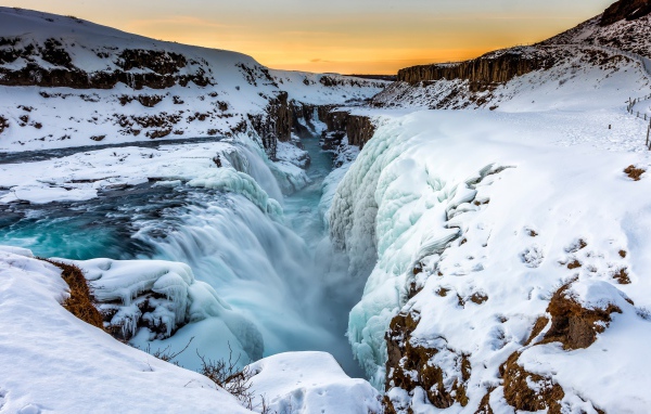 Заледеневший водопад у покрытых снегом берегов, Исландия