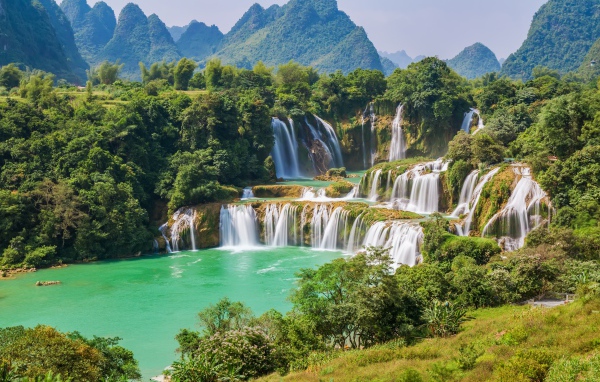 Водопад стекает с гор на фоне зеленой природы