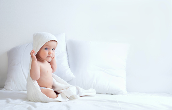 Грудной ребенок сидит на кровати с подушками