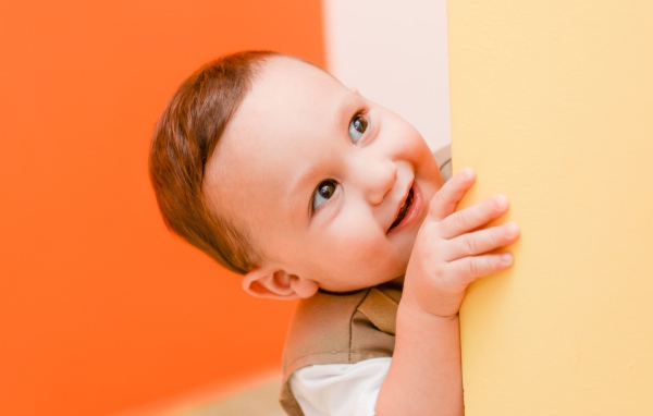 Маленький любопытный мальчик выглядывает из-за стены