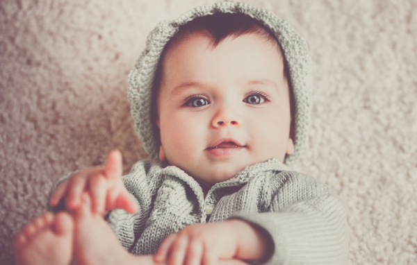 Маленький милый голубоглазый малыш в вязаном костюме