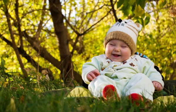 Смеющийся грудной ребенок сидит на траве