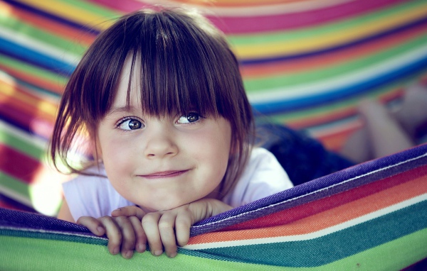 Маленькая кареглазая девочка лежит в гамаке