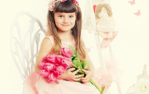 Красивая милая голубоглазая девочка с букетом розовых тюльпанов