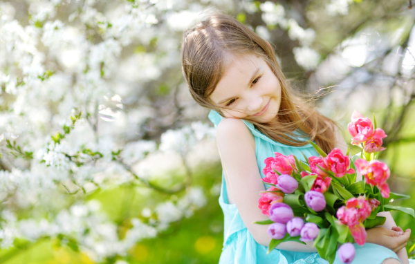 Красивая маленькая девочка с букетом тюльпанов весной