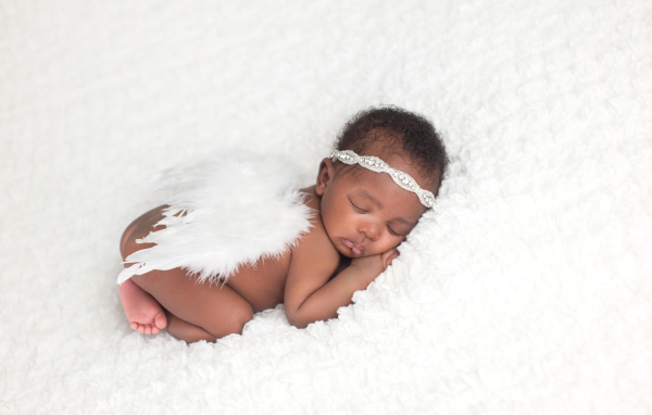 Темнокожий младенец спит с крыльями ангела