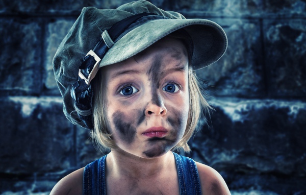 Смешная девочка в кепке с грязным лицом