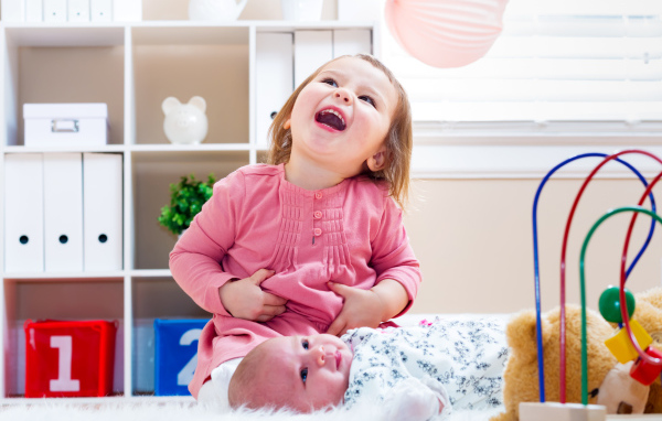 Смеющаяся маленькая девочка с младенцем