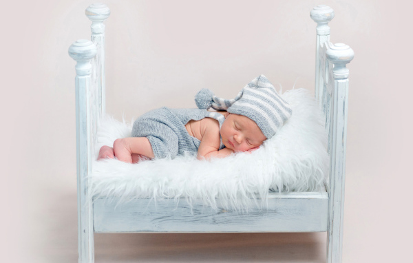 Маленький грудной ребенок спит в маленькой кроватке
