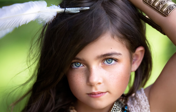 Маленькая красивая девочка с белым пером в волосах