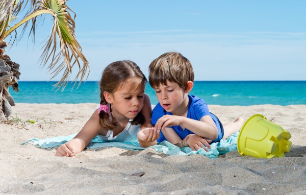 Маленькие мальчик и девочка играют на песке на пляже