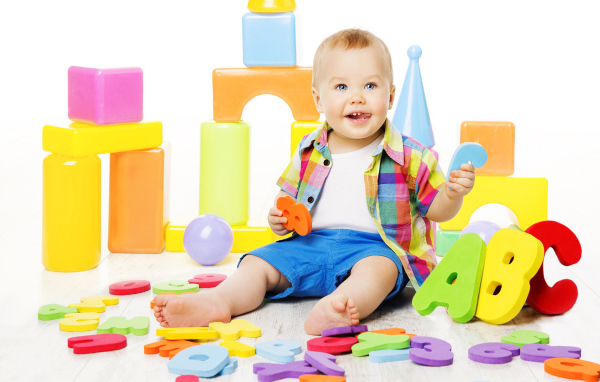 Маленький мальчик играет с разноцветными игрушками 