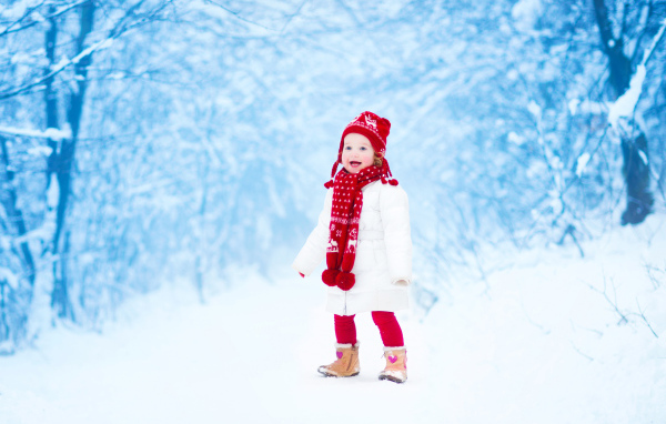 Маленькая веселая девочка в зимнем лесу