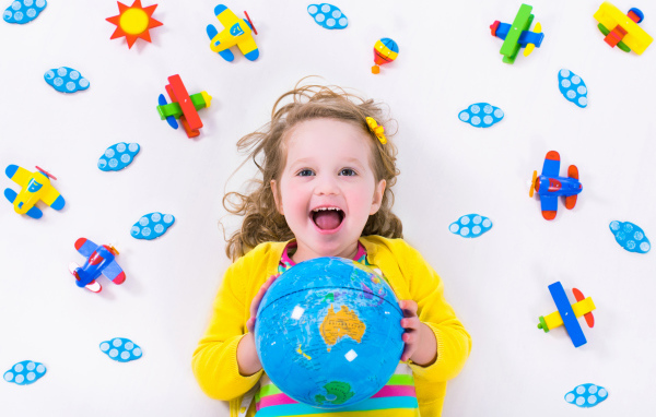 Маленькая веселая девочка с глобусом в руках 