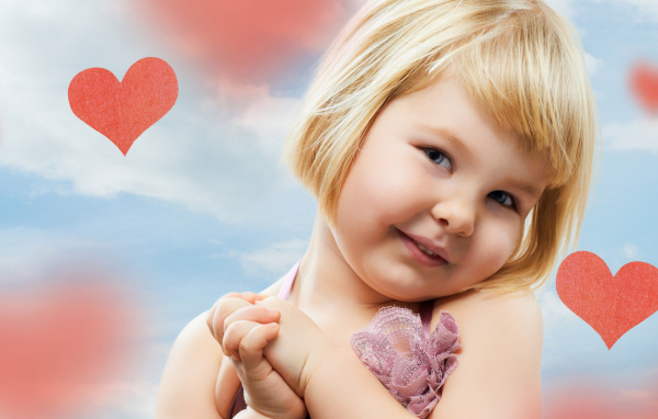 Маленькая милая девочка на фоне красных сердечек