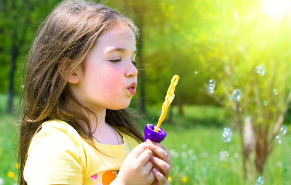 Маленькая девочка пускает мыльные пузыри