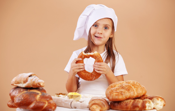 Маленькая девочка в костюме повара и свежей выпечкой