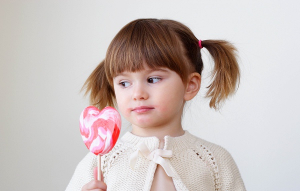Маленькая девочка с большой конфетой на палочке