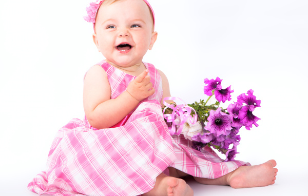 Маленькая улыбающаяся девочка с букетом петунии на белом фоне