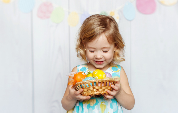 Маленькая улыбающаяся девочка с пасхальными яйцами в руках