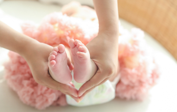 Маленькие ножки новорожденного в ладонях у мамы 