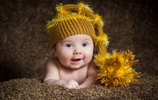 Улыбающийся малыш в красивой вязанной шапке 