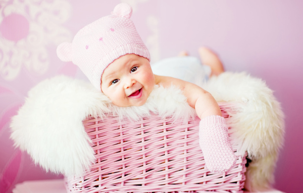 Улыбающийся грудной ребенок лежит в розовой корзине