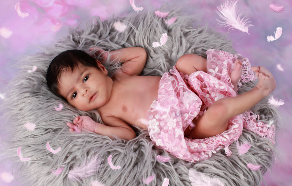 Младенец лежит на сером меховом покрывале 