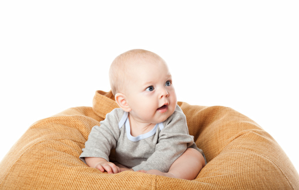 Младенец сидит на подушке на белом фоне