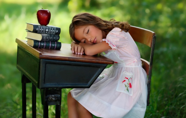 Уставшая маленькая ученица уснула за партой