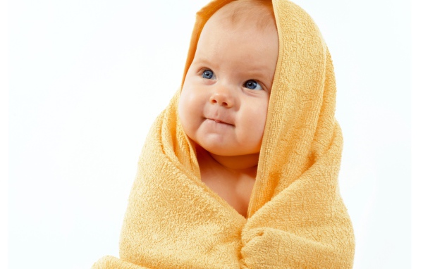 Грудной ребенок в желтом полотенце на белом фоне