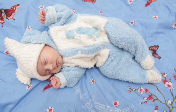 Грудной спящий ребенок в голубом костюме