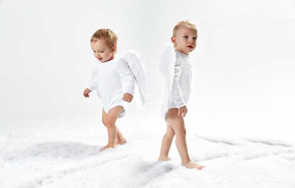 Два маленьких мальчика в костюмах ангела на белом фоне
