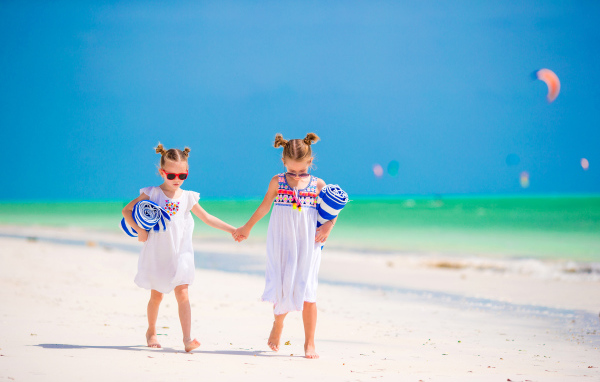 Две маленькие девочки идут по песку