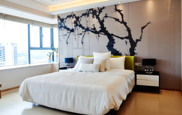 Красивая светлая спальня с большой кроватью и рисунком на стене 