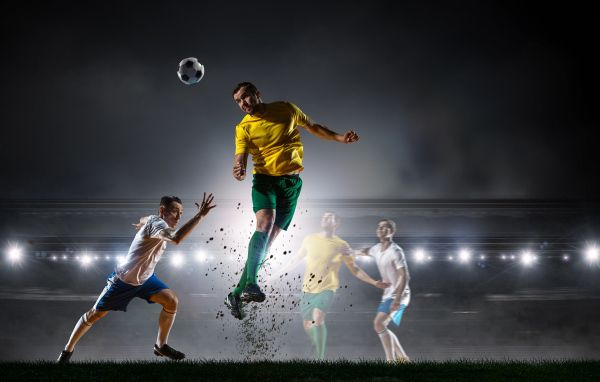 Футболист отбивает мяч на поле во время игры