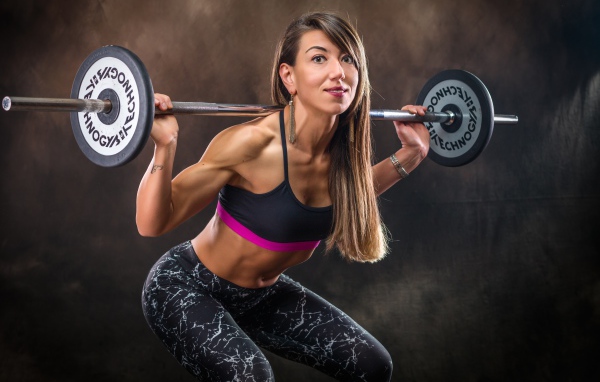Спортивная накаченная девушка со штангой 