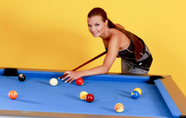 Молодая девушка играет в бильярд