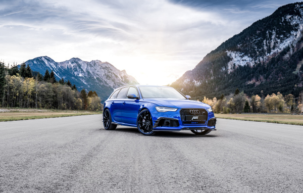 Синий автомобиль Audi RS 6 на фоне гор на дороге