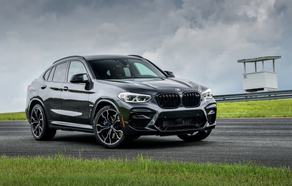 Черный автомобиль  BMW X4 M Competition, 2020 года на фоне грозового неба
