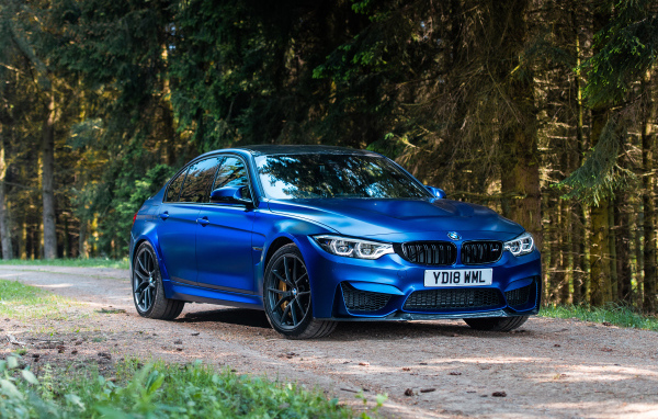 Синий автомобиль BMW M3 на фоне деревьев