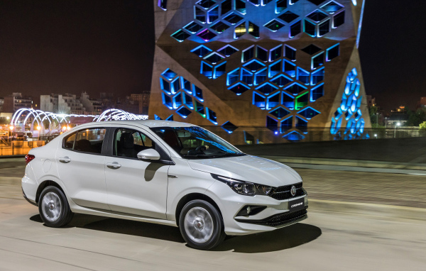 Белый автомобиль Fiat  Cronos, 2018 года на фоне здания