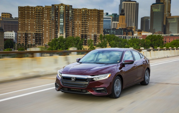 Бордовый автомобиль Honda Insight на фоне города