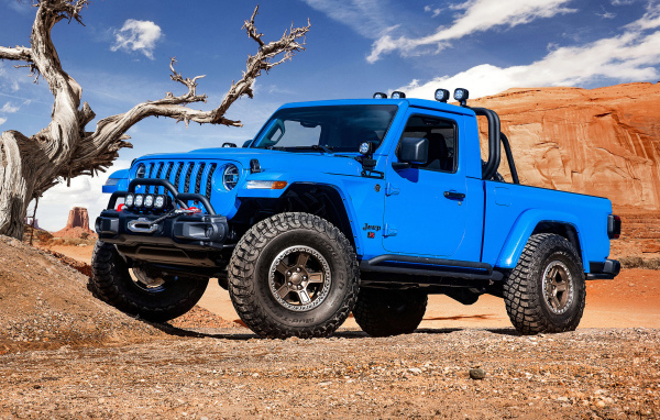 Синий пикап Jeep J6, 2019 года на фоне гор у сухого дерева