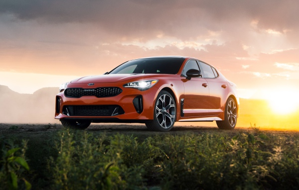 Оранжевый автомобиль  Kia Stinger GTS, 2020 года на закате